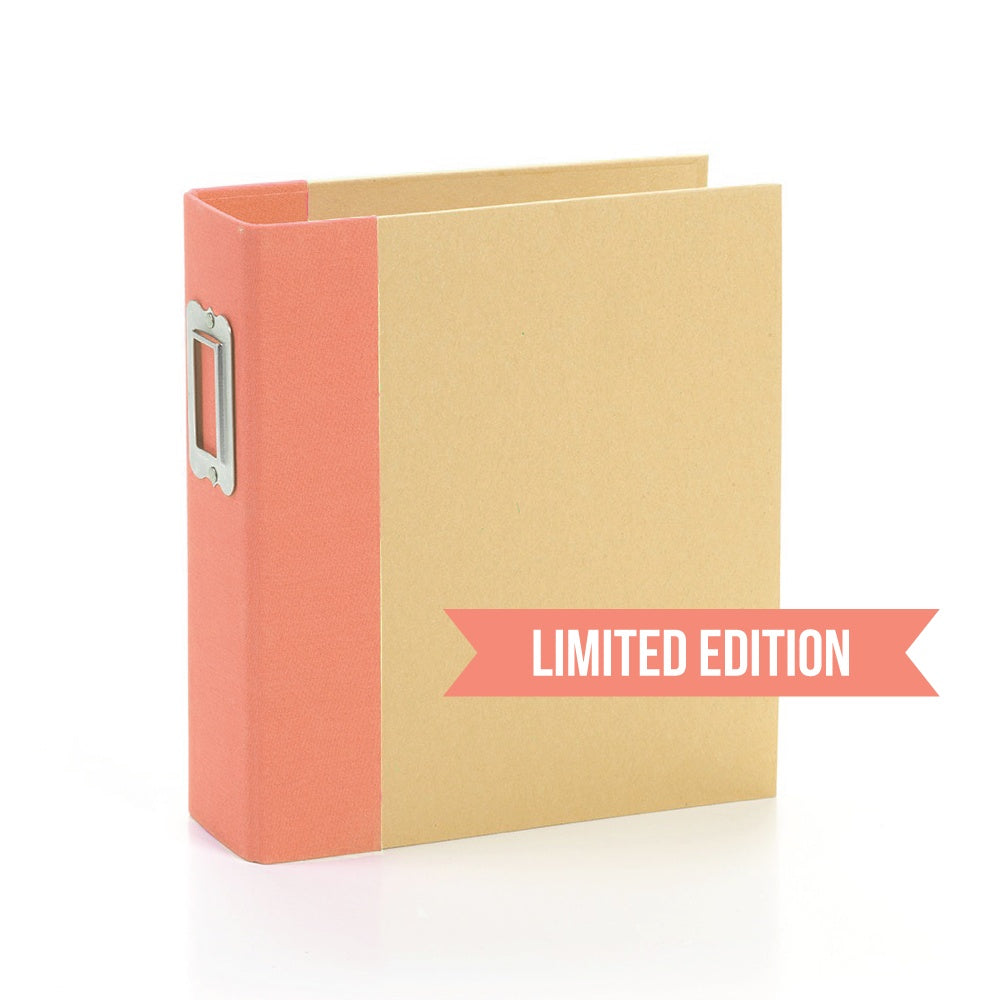 A coral-colored binder with a limited edition label on the front, featuring a snap closure.